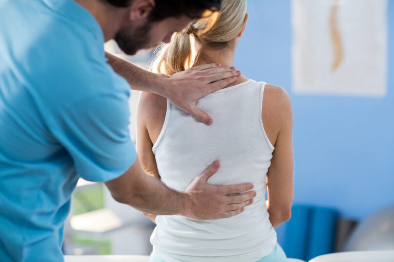Male physiotherapist giving back massage to female patient 804248